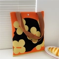 Close-up of floral knitted tote bag with brown straps and silver snap button closure - Clover Orange
