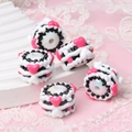 Macro shot of white acrylic cylindrical beads with black waves and pink hearts - Black White Cream Rose Red Heart