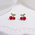 Detailed view of red cherry earrings on a white tray with silver stems and green leaves - Red Cherry Stud Earrings