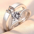 Close-up of silver-plated couple rings with round-cut crystals on soft beige fabric - Angel