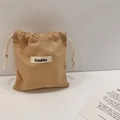 Close-up of khaki canvas drawstring pouch with woven logo label and cotton-linen texture - Brown