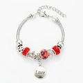 Detailed view of the red crystal beads and heart-shaped charms on the silver LOVE bracelet - Red