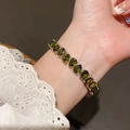 Close-up of olive green pear-cut gemstone bracelet on a wrist with white lace sleeves - 49# Bracelet - Silver - Green