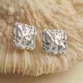 Hammered silver square earrings with small flower details on beige coral surface - Silver Square Hammered Style