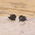 Macro shot of black cartoon ghost stud earrings on natural pink stone background - Black