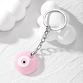 Détail d'un porte-clés œil grec rose en résine avec anneau et chaîne en métal argenté - Œil en Verre Rose