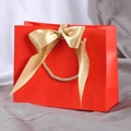 Elegant red paper gift bag featuring a luxury gold satin bow and braided handles - XS (19x15x7cm) / Red