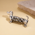 Macro detail of silver dachshund brooch featuring tricolor braided rope on metal - Silver