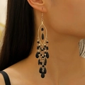 Detailed close-up of Bohemian gold tassel earrings with black beads on a model - KC Gold S555