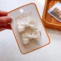 Détail de barrettes noeuds en tissu crème avec perles sur carte de présentation - Paire de nœuds en mousseline de perles