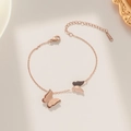 Elegante bracciale a farfalla in oro rosa con ciondoli opachi e lucidi su sfondo beige - Stile Farfalla (929)