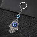 Detailansicht eines silbernen Hamsa-Hand-Schlüsselanhängers mit blauen Evil-Eye-Perlen - Großes Auge Hamsa