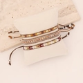 Detail of bohemian hand-woven seed bead bracelets on a white display pillow - Brown