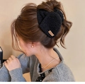 Dettaglio molletta per capelli nera in peluche con etichetta in pelle su uno chignon - Stile Molla / Nero (Etichetta YYDS)