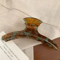 Close-up of French acetate hair claw clip with amber and green leopard print texture - Amber Green