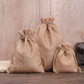 Three sizes of natural linen drawstring bags with cotton rope closures on a wooden table - Earthy Yellow