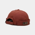 Detail showing rust red canvas fabric texture and retro patch on the brimless docker cap - Adjustable / Brick Red