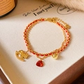 Macro shot of double-layered red rope bracelet with golden pony and heart stone charms - 18K Gold Plated Double Layer Horse Style / Gold-Red