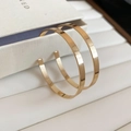 Makro-Detail von breiten goldenen C-Ohrringen mit poliertem Spiegel-Finish - Silbernadel-Stil / Gold