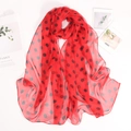 Dettaglio di una leggera sciarpa in chiffon rosso con eleganti pois neri e texture - Rosso