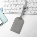 Grey PU leather luggage tag with lychee texture and matching strap on white desk - Vertical Flip Style / Gray