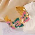 Détail du papillon en émail rose et vert sur un bracelet doré avec finition satinée - Rose et Vert