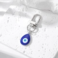 Detail van blauwe boze oog sleutelhanger met zilveren sluiting op stenen achtergrond - Zilver Waterdruppel Donkerblauw Boze Oog