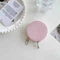 Detailed view of a round pink textured leather coin purse with silver zipper on a white table - Pink