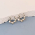 Detailed close-up of heart-shaped silver earrings on a white textured stone surface - Silver Linked Hearts