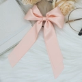 Detailed view of pink satin ribbon bow hair clip on a soft white faux fur background - Pink