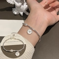 Silbernes Armband mit gedrehter Kette, weißer Perle und Herzanhänger am Handgelenk - Bambus Perle Herz