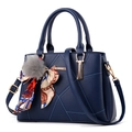 Blue geometric stitched handbag with fur ball charm and silk scarf on white background - Dark Blue