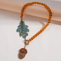 Primer plano de cuentas ámbar con dijes de hoja y piña de cristal en cadena larga - Collar de Cuentas de Bellota y Hoja (Collar-Marrón)