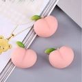 Set of three pink peach squishy toys made of TPR soft resin on a magazine page - Peach Series