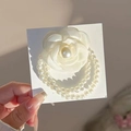 Détail d'un chouchou fleur camélia blanc avec doubles chaînes de perles blanches sur carte - Style Perle Camélia / Blanc Cassé