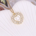 Macro detail of gold heart pendant with zircon border and white enamel smiley face - White