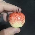Miniature red and yellow artificial apple prop with glossy finish held by hand - Mini Pink Apple