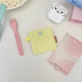 Close-up of yellow quilted headphone pouch with blue heart button and side logo tag - Heart Yellow