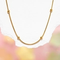 Detail of a polished gold snake chain necklace featuring five evenly spaced golden beads - 1.5mm Bead Chain