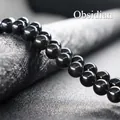 Macro shot of polished natural black obsidian beads showing uniform texture and glossy finish - Obsidian