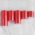 Close-up of multiple stacked red polyester satin ribbons on white marble background - 1cm Wide 10 Rolls Satin Ribbon 22m