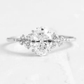 Macro shot of oval-cut zircon and small accent diamonds on a polished S925 silver ring band - US Size 9 / White Gold