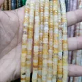 Close-up of natural yellow stone spacer beads with cylindrical shape and smooth texture - Yellow Aventurine