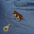 Macro shot of gold-plated knot jewelry set with necklace and earrings on blue satin - E6107-3/Gold Braid Knot Texture