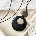 Detailed close-up of a minimalist agate pendant necklace on a beige suede gift box - Black and Green (Flat Round Pendant)