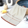 Absorbent beige cotton towel with colorful striped border placed on a bathroom counter - Cotton Fine Weave Tri-Color Cream (Gift Pack)