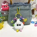Primer plano de un llavero de peluche blanco con gafas de sol colgado en un bolso vaquero - Blanco