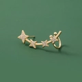 Gros plan sur un protège-oreille doré avec quatre étoiles en zircon sur fond vert foncé - Style Manchette d'Oreille Étoile (NE1093)