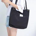 Black corduroy tote bag with white patch label shown on model for casual daily use - Black