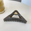 Detail of a large 12cm transparent brown triangular hair claw with a gold metal spring - Dark Gray